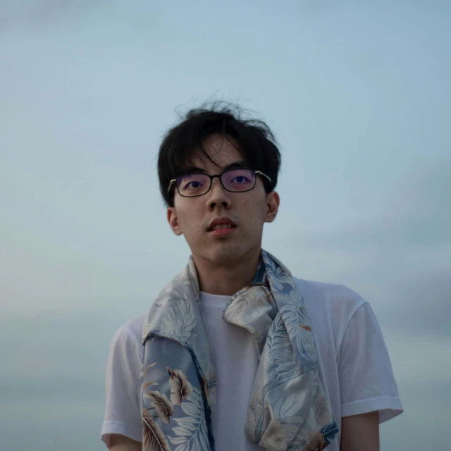 a man standing on a beach wearing a scarf