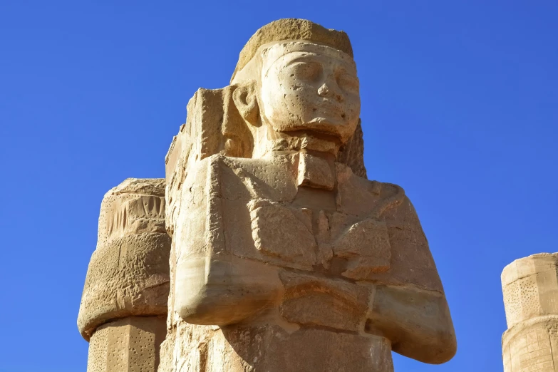 the statue is in the blue sky behind some tall pillars