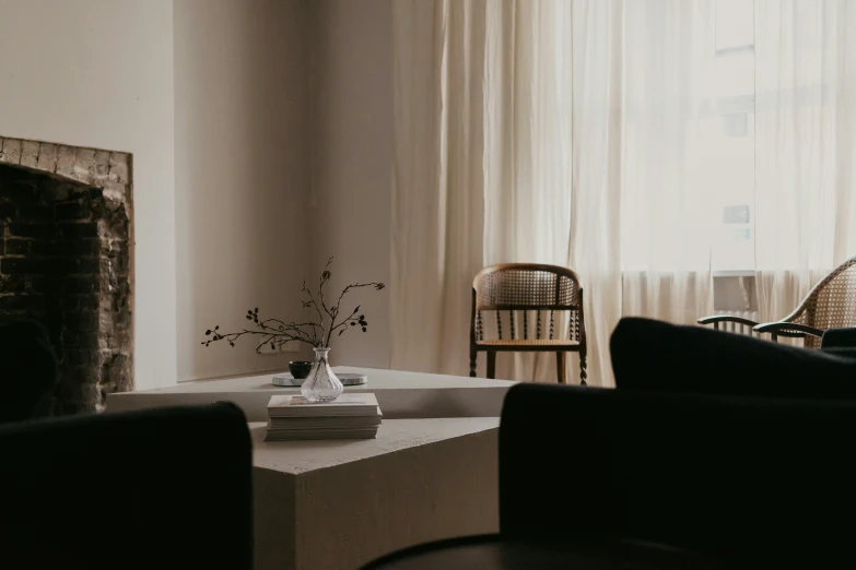 a living room with chairs, table, fireplace, and curtains