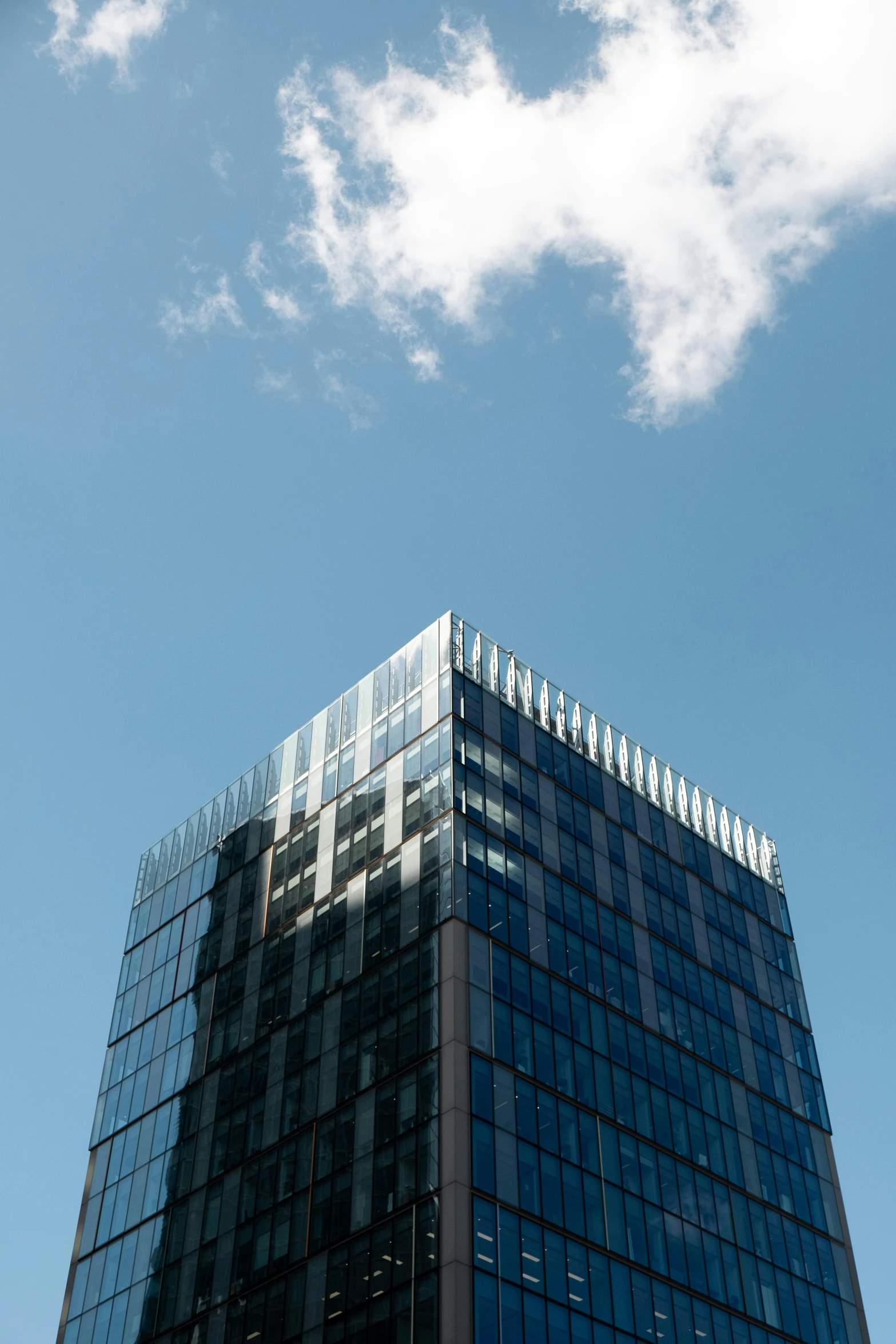 a tall blue and black building with a sky in the background