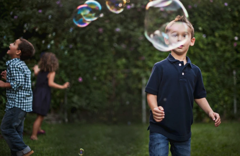 several little s playing with soap bubbles in the yard