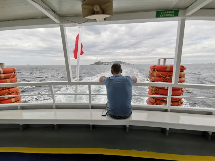 the man is sitting on a boat looking out at the water