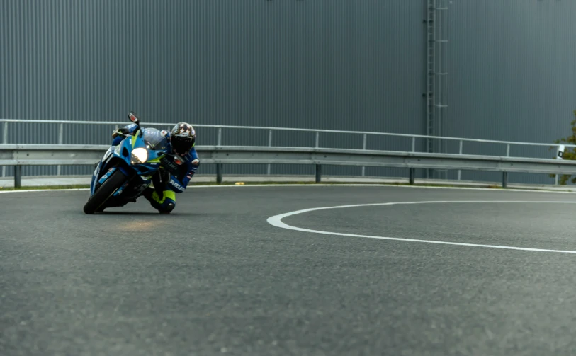 man riding blue and yellow motorcycle on roadway