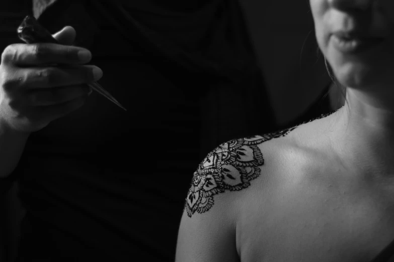 a black and white po of a woman getting a tattoo