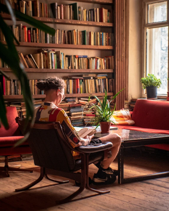 man sitting on an easy chair in front of a bookshelf