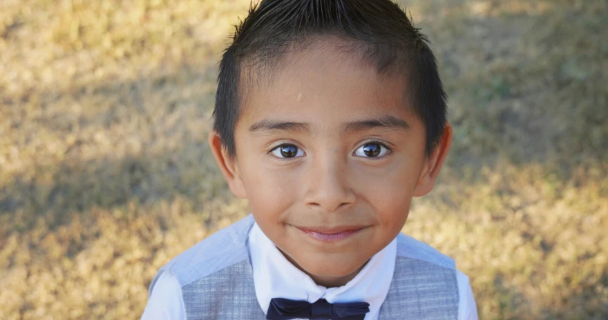 a boy smiling for the camera with a bowtie on