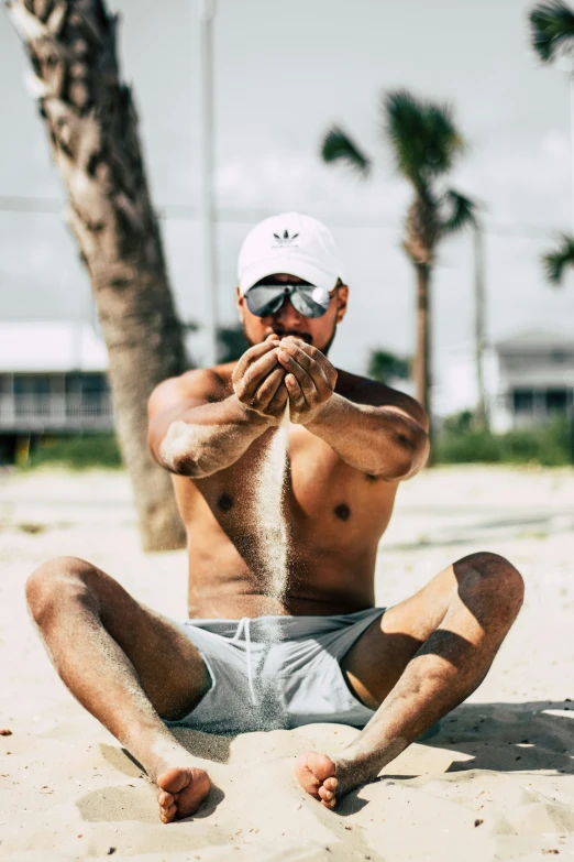 a man sitting on a beach next to a palm tree