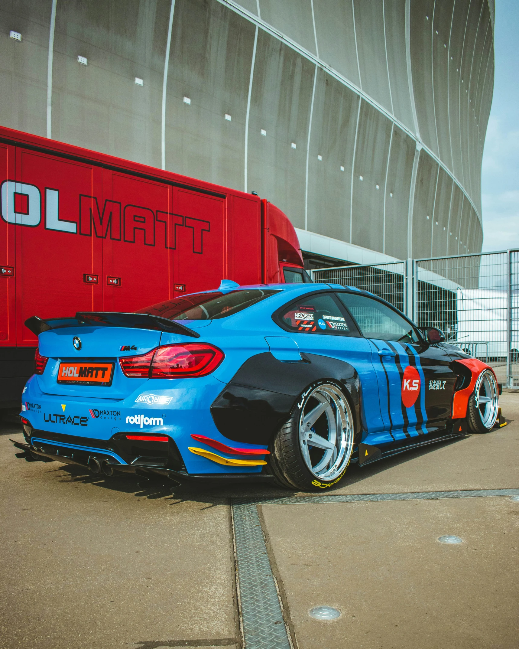 the bmw has a colorful racing car in front of it