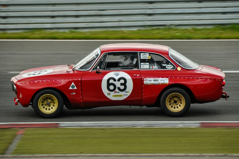 a vintage red race car driving around a track