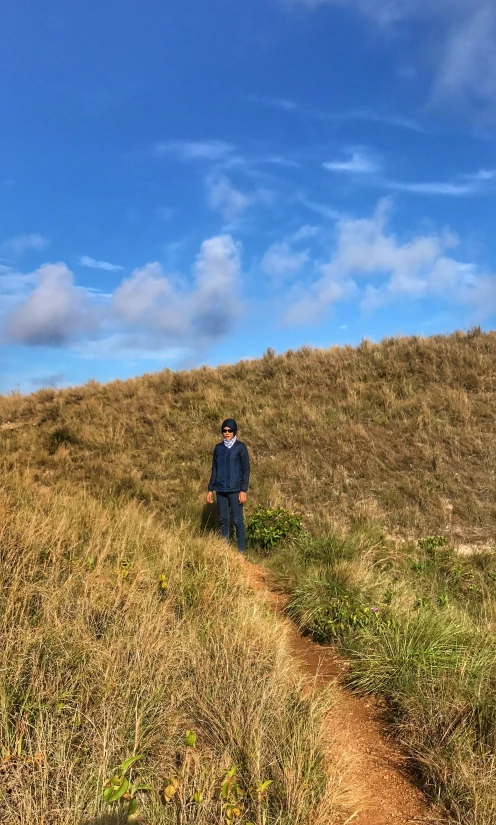 a man walks in a field and wears a jacket