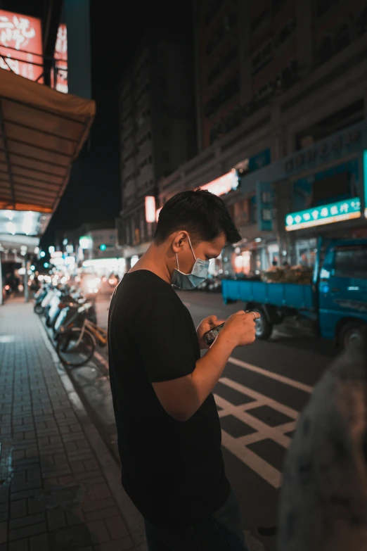 man using cell phone on busy city street at night