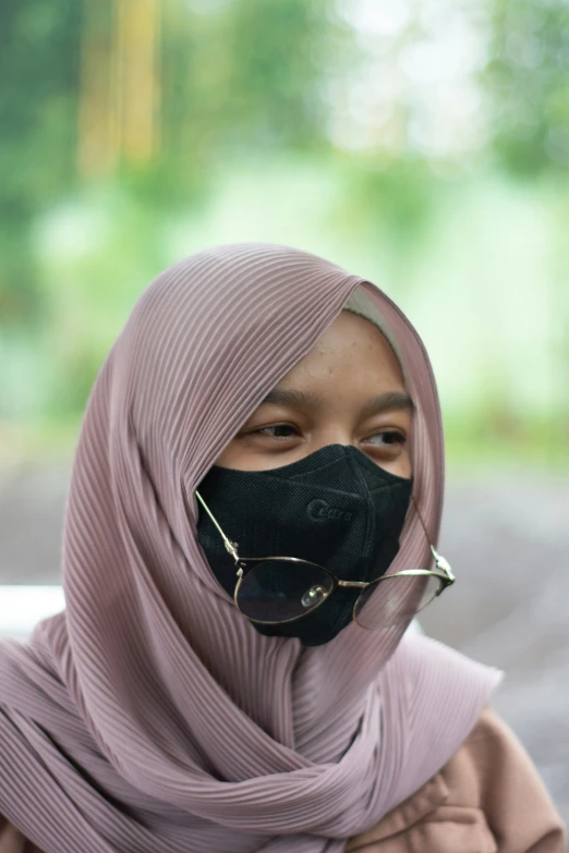 a woman in a black mask is wearing a gray scarf