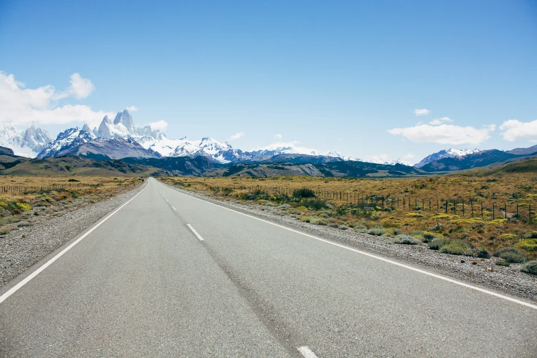 the long empty road has a mountain in the distance