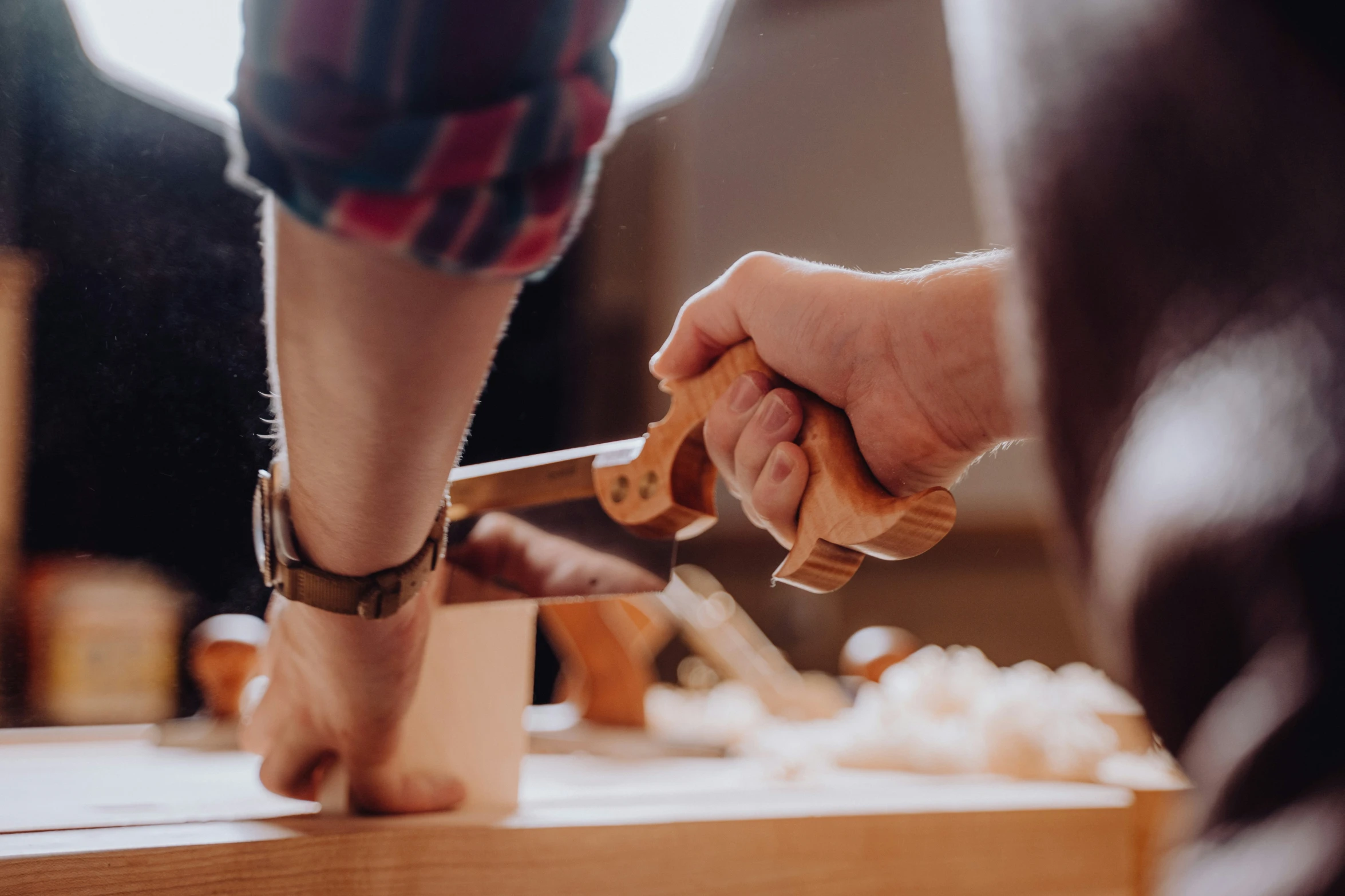 person using wooden  knife in woodworking shop