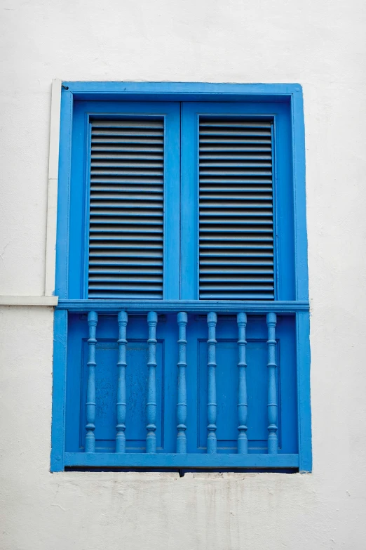 a blue window with a green shutter on a white wall