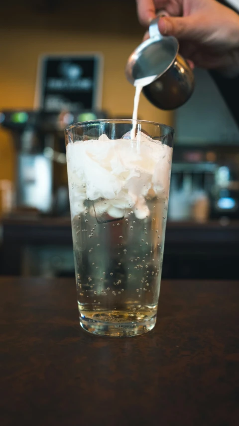 a man pours ice water into a glass filled with soda