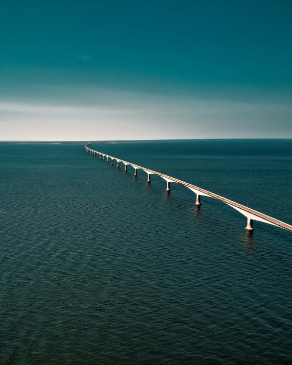 a bridge spans over the water from a high cliff