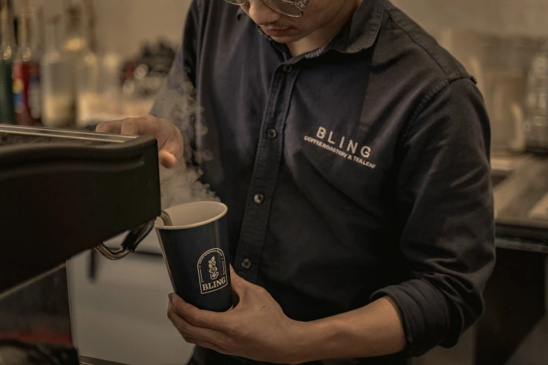 a man holding a cup of liquid standing next to a counter