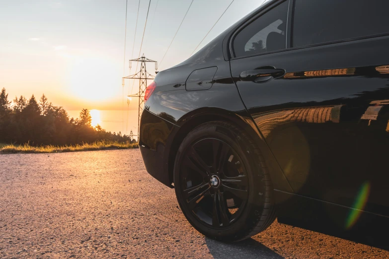 a black car parked at sunset on the side of a road