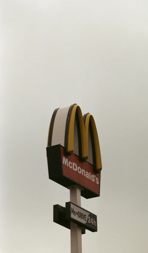 a mcdonald's sign sits below a cloudy sky