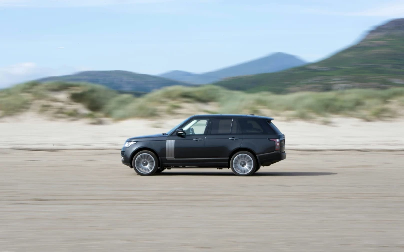 a black land rover driving through the desert