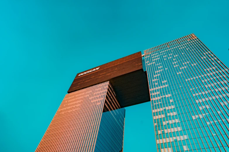 the top of two tall buildings against a bright blue sky