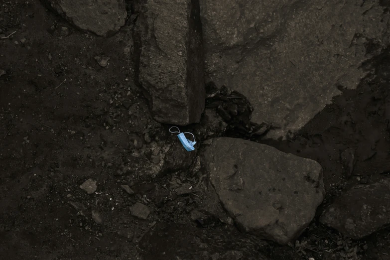 a blue and black object sitting on a rocky beach