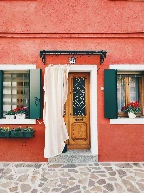 a red building with green shutters and two windows