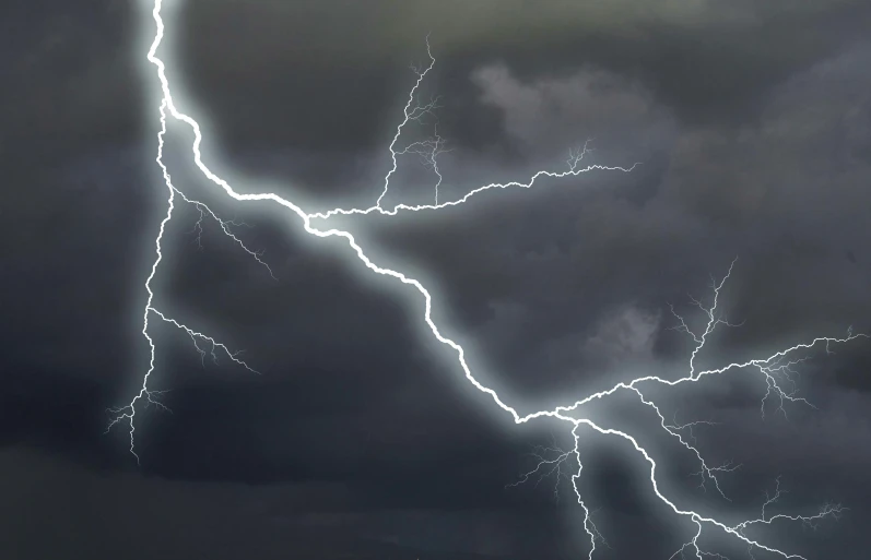 a cloud with lightning strikes behind a train