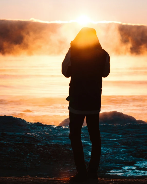 a man standing on top of a beach at sunset