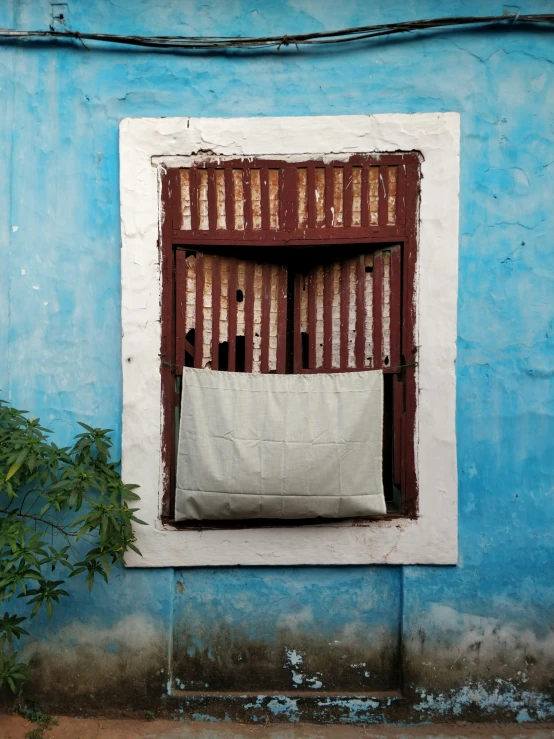 a small window sitting on the side of a blue wall