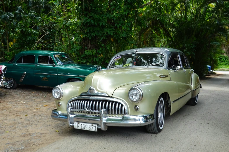 green and white classic cars on dirt area