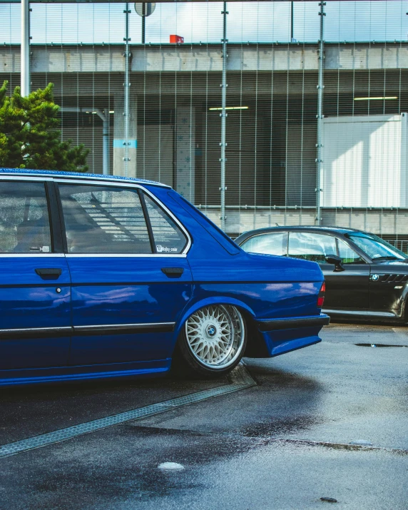 blue cars are parked at a curbside near a building