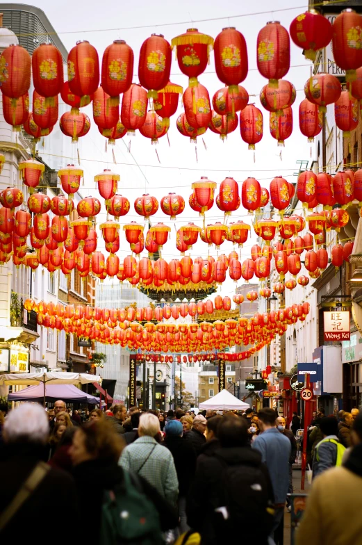 many people walking on the street under red lanterns