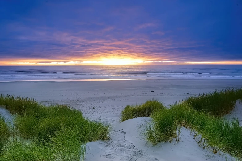 there is a sunset over the ocean on a beach