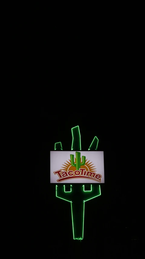 an illuminated sign advertising green beverages against a black background