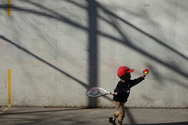 a child walking down a street holding a tennis racket