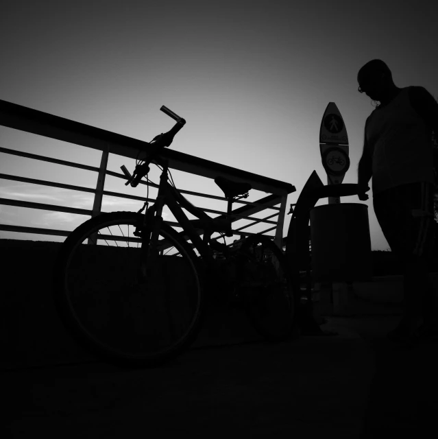 a black and white po of man with bike next to skateboard