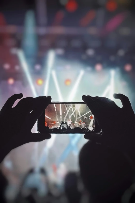 someone taking a picture on their phone while they perform in the spotlight