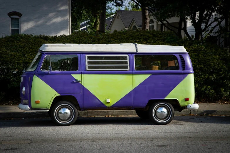 a van painted in purple, green and white is parked in a street