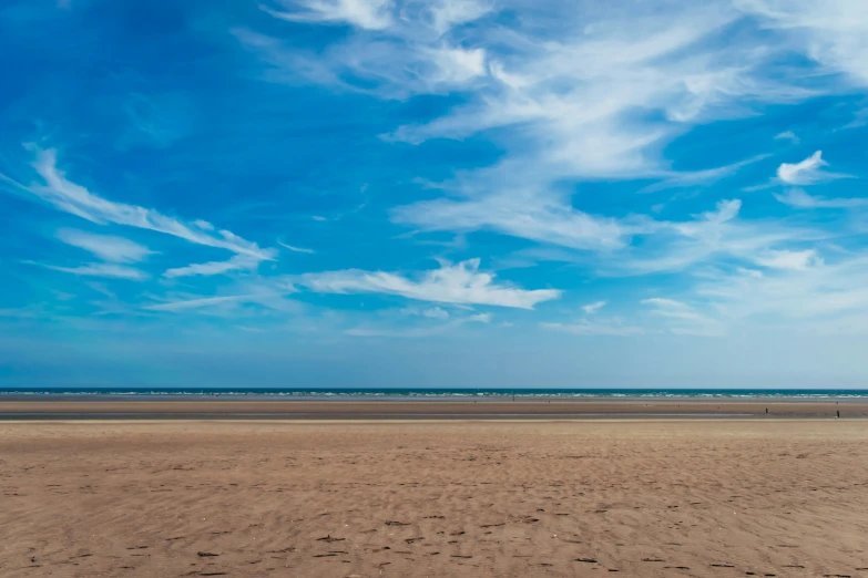 a large beach with a person holding a surfboard