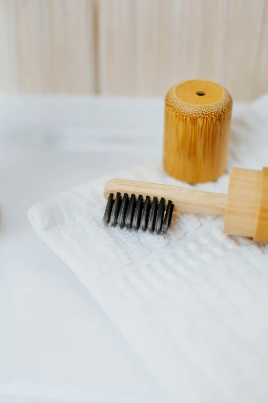 a wooden brush laying on top of a towel next to an odd shaped wooden holder