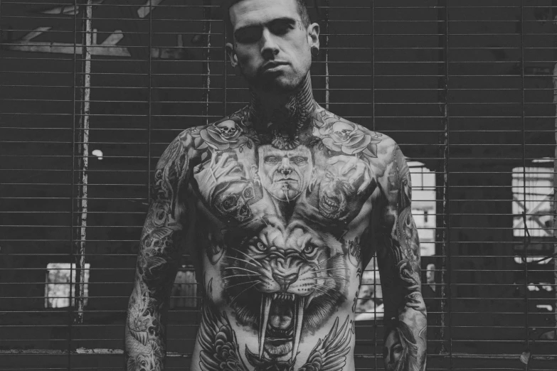 a tattooed man posing for a po in front of some bars