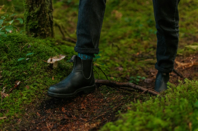 a person wearing a pair of black shoes standing on green grass