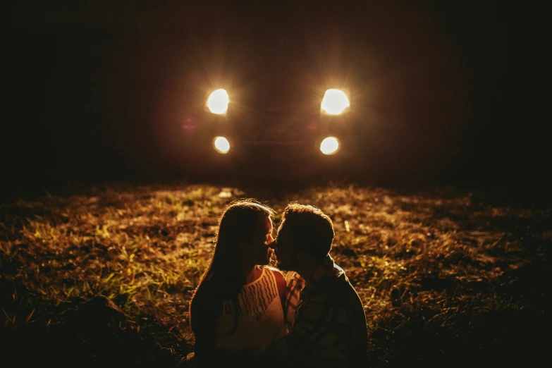 two people sit on the grass under spotlights