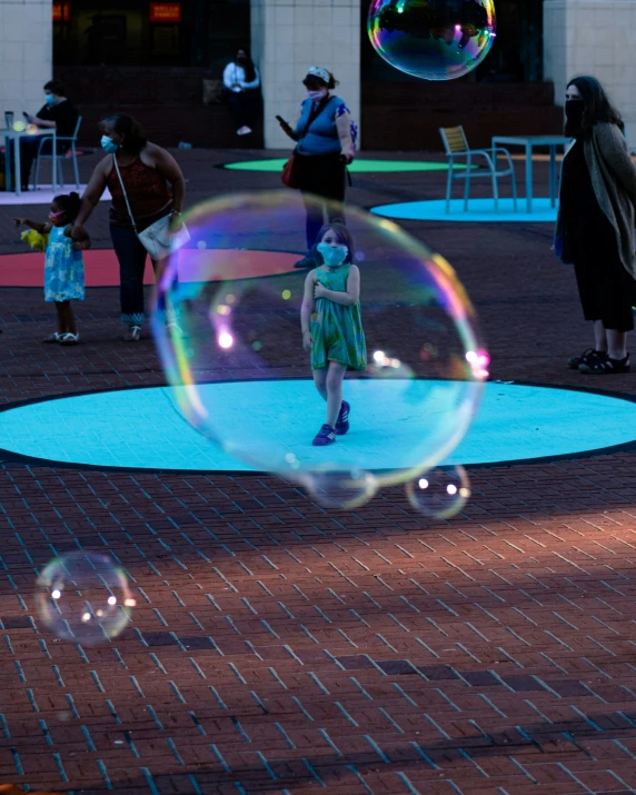 a little girl in a dress walks in front of soap bubbles floating