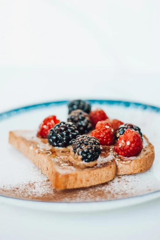 a plate of toast with berries and powdered sugar