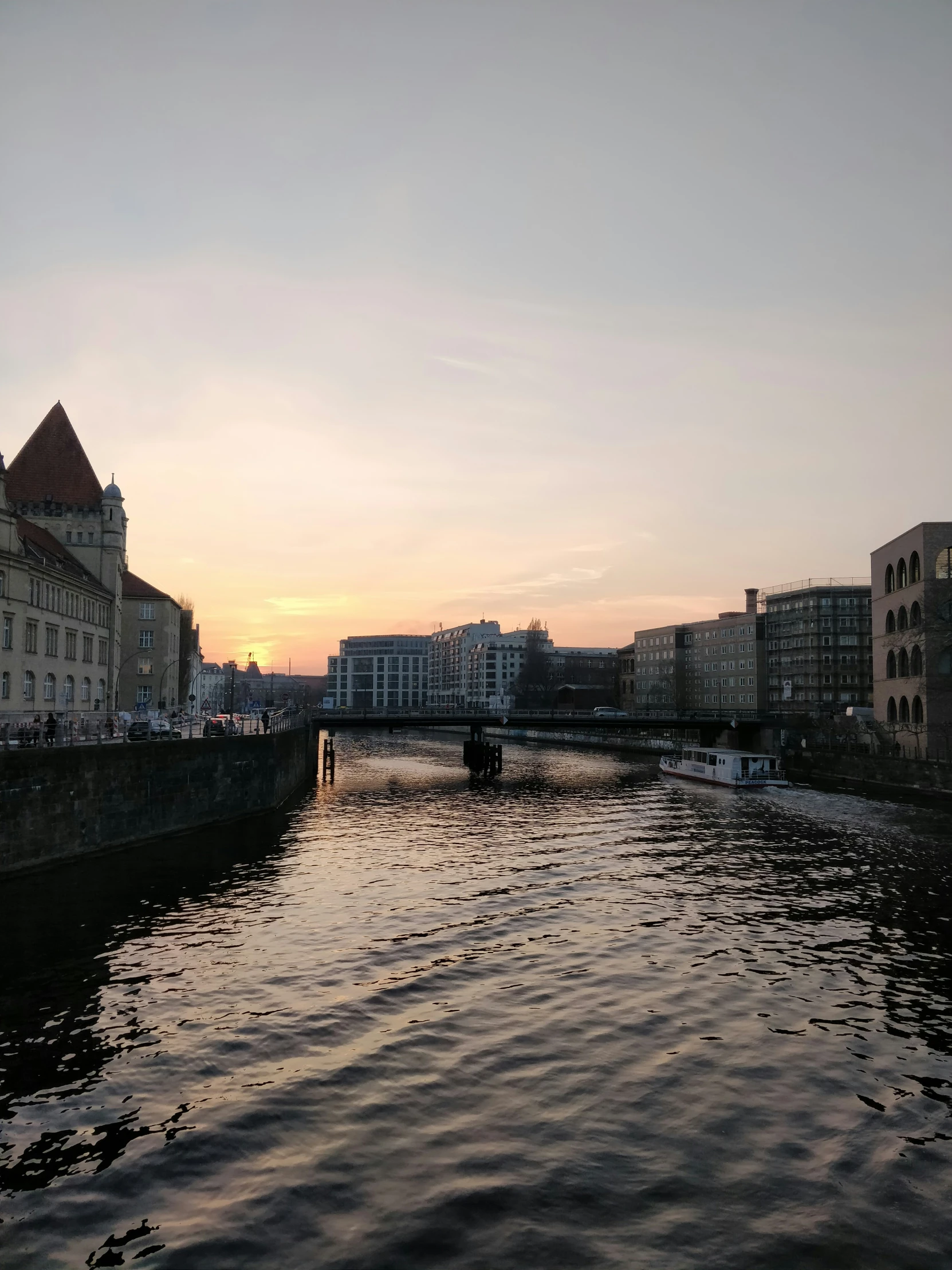 the sun is rising over a waterway with several buildings and bridge