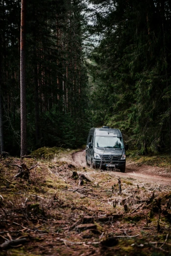 an van driving on a trail through a forest