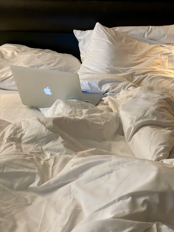 an image of the bed that is unmade and has laptop